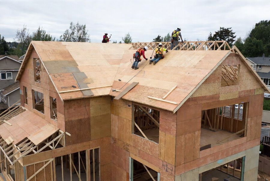 Roofing crew installing decking on a new construction home