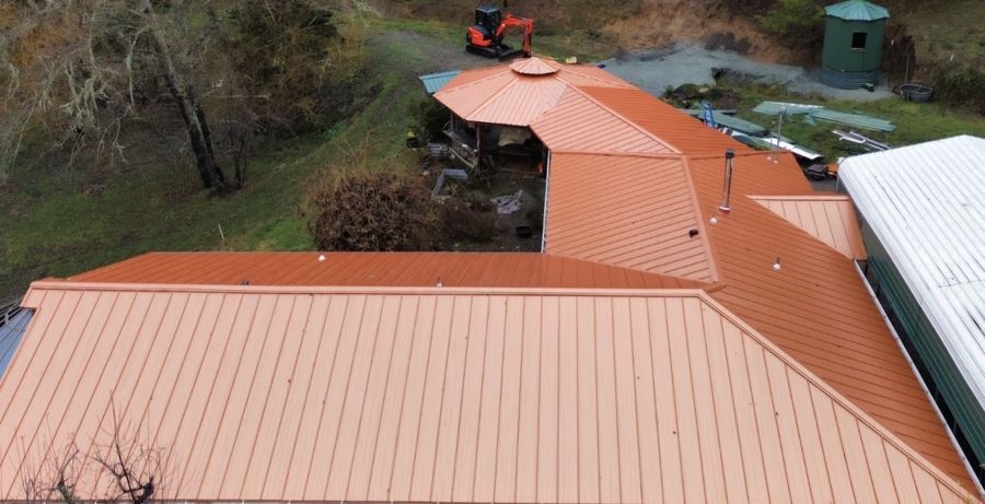 Terracotta standing seam metal roof with excavator on site