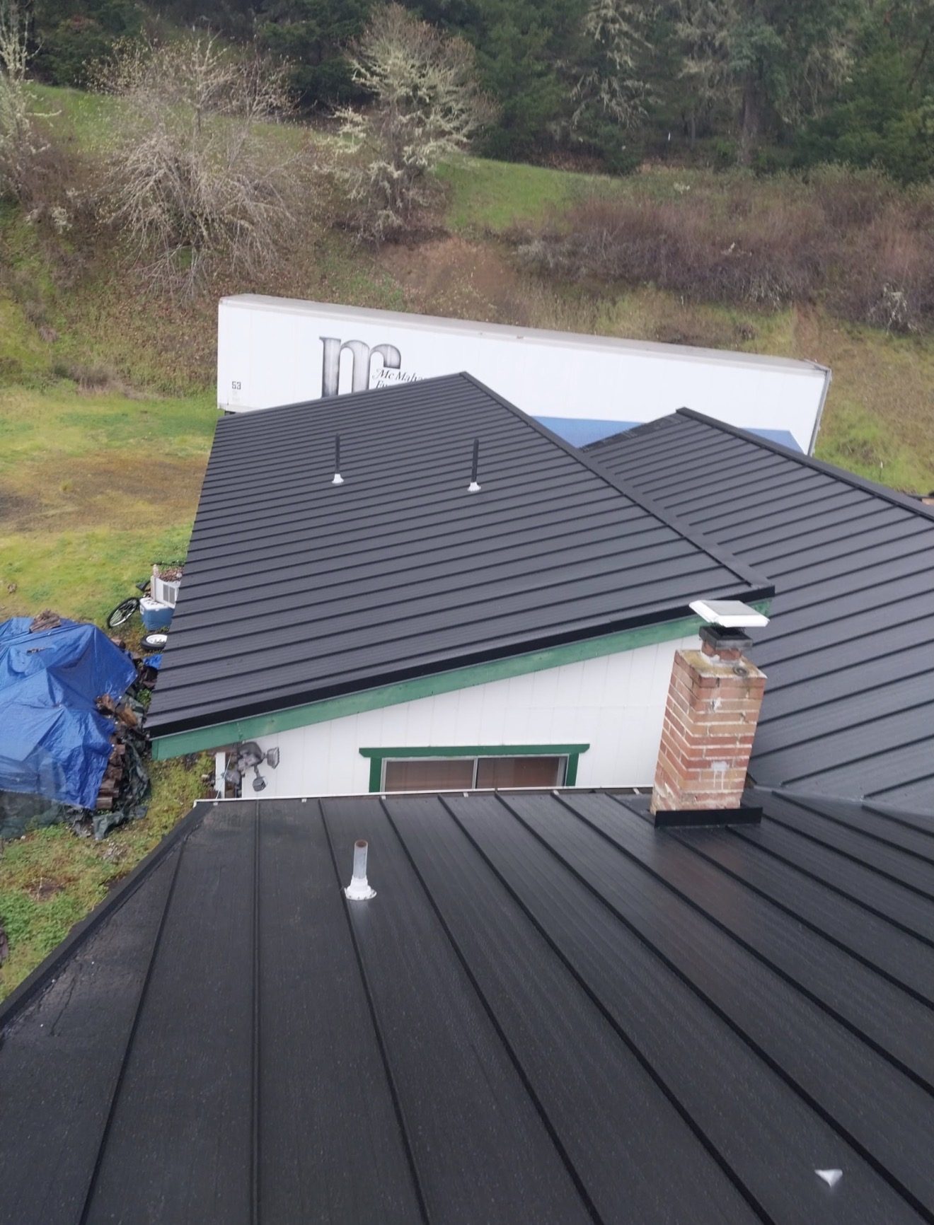 Black standing seam metal roof with brick chimney
